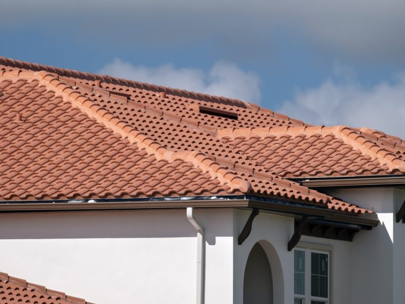 Overlapping rows of yellow ceramic roofing tiles covering residential building roof in southern Florida.